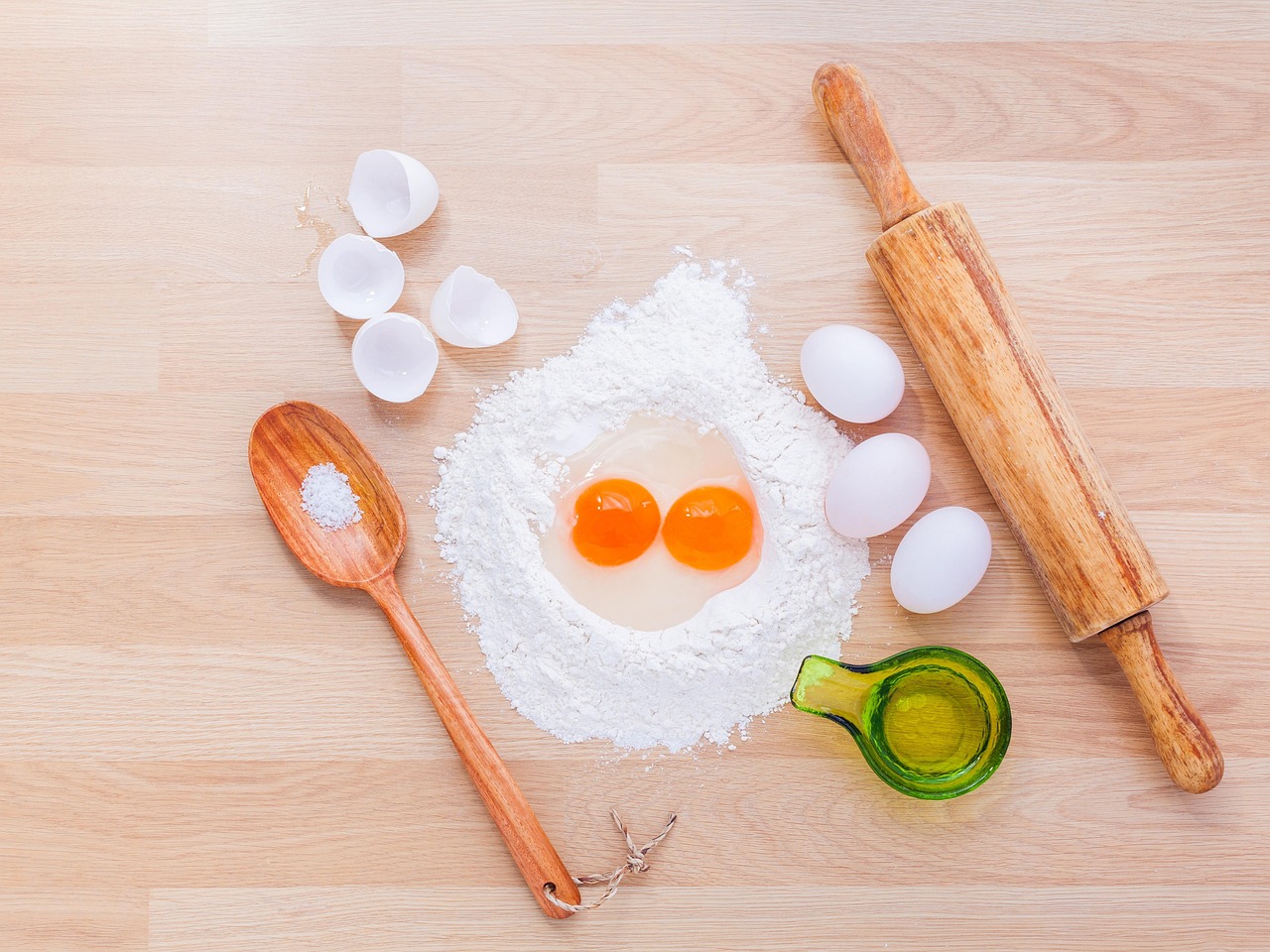 Hands rolling out dough with ingredients nearby.