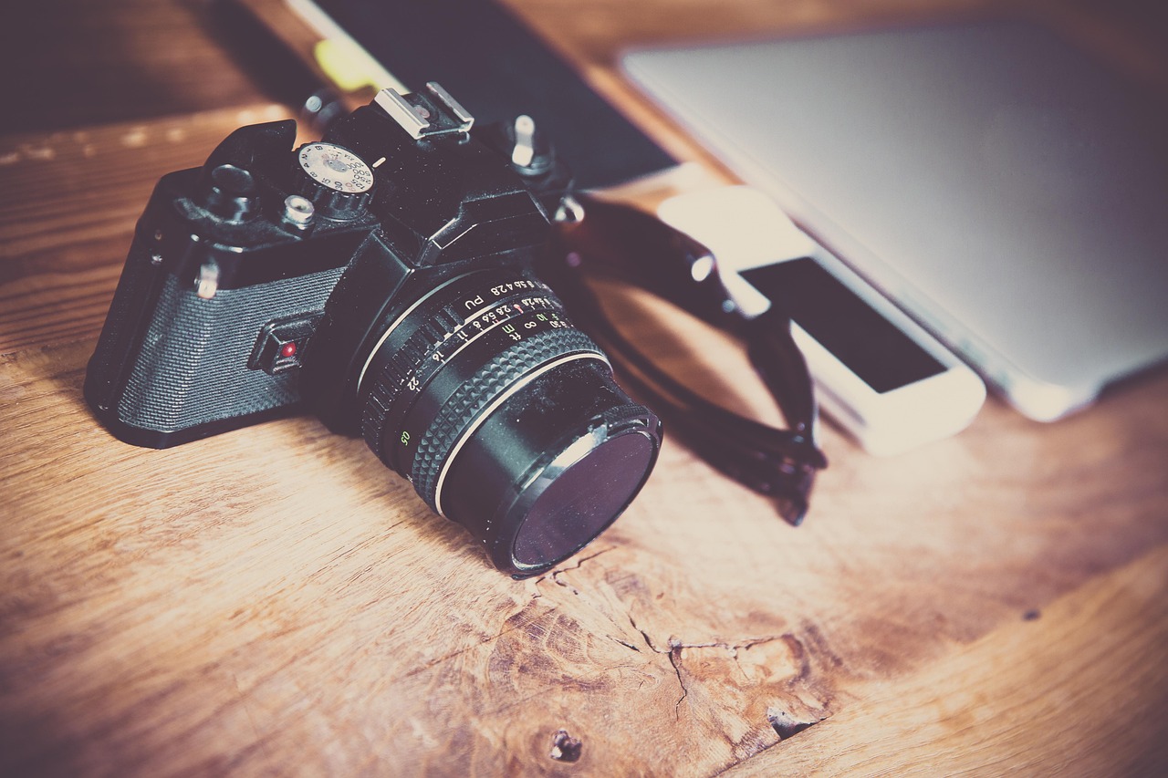Vintage film camera on a wooden desk with a laptop